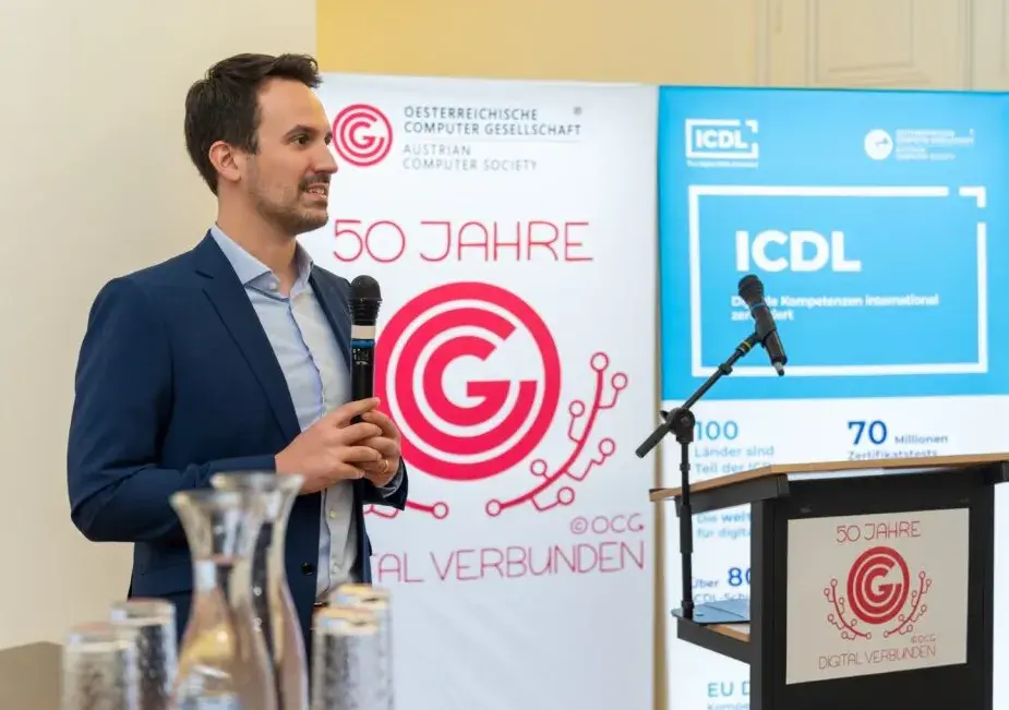 Bildungsminister Wiederkehr vor OCG und ICDL Banner