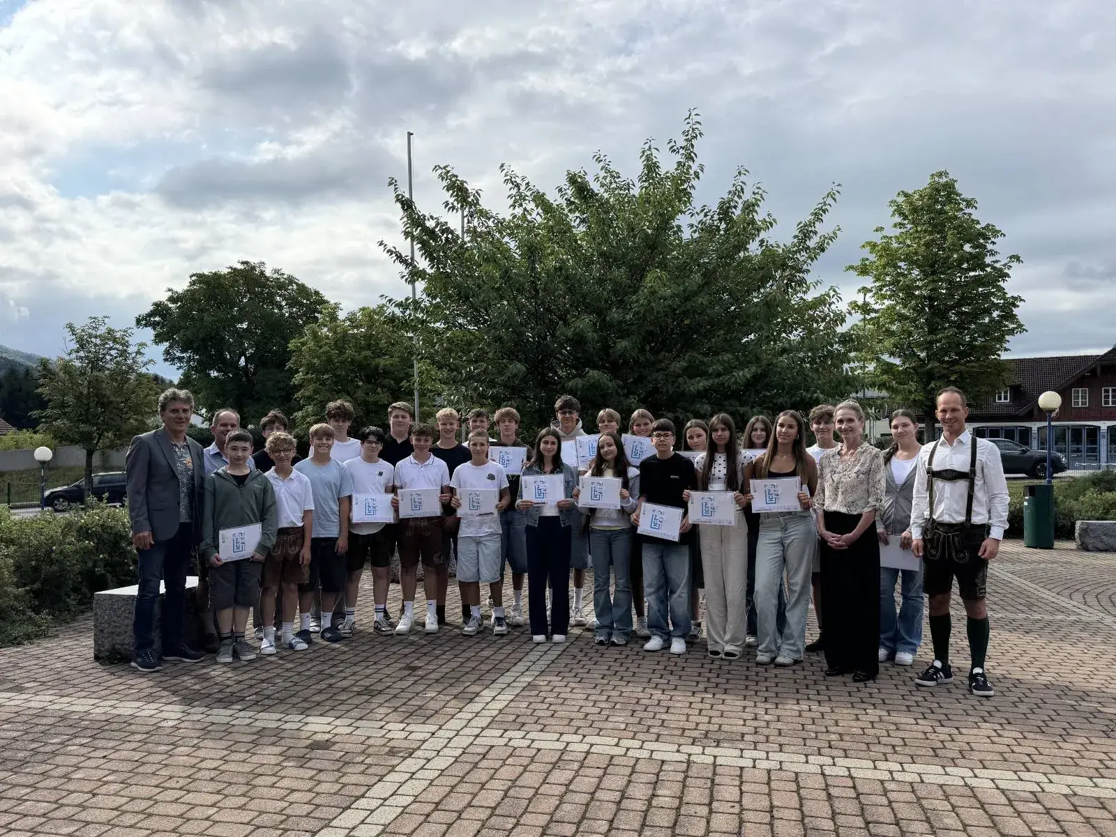 Gruppenfoto: 24 Schüler*innen posieren mit ihren ICDL Zertifikaten mit Direktion, Lehrern und Christine Haas