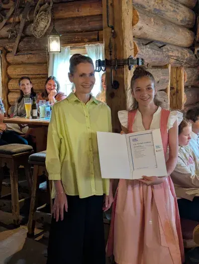 Christine Haas mit einer Schülerin der MS Lend, ICDL Zertifikat wird präsentiert, in einem rustikalen Lokal. 