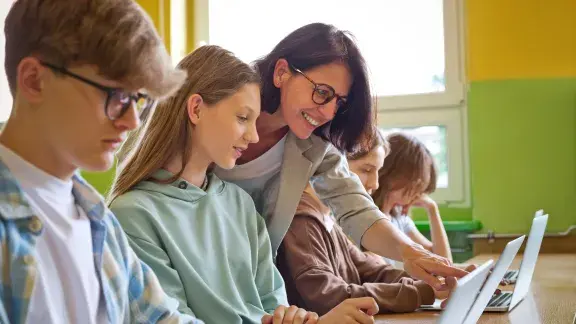 Oberstufen-Schüler*innen benutzen Laptops im Klassenzimmer, Lehrerin zeigt etwas, Schüler*innen, 14-15 Jahre, Stockfoto