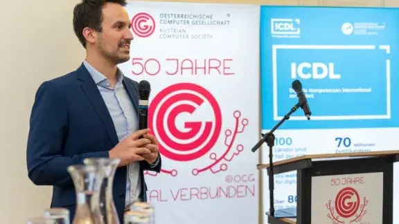 Bildungsminister Wiederkehr vor OCG und ICDL Banner