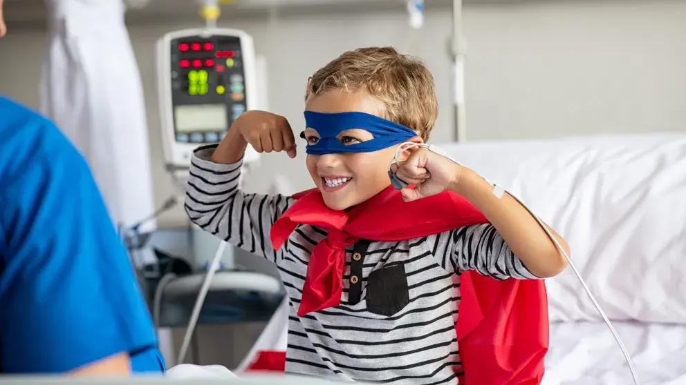 Verspieltes Kind im Superhelden-Kostüm in der Klinik überwindet Widrigkeiten und gesundheitliche Herausforderungen