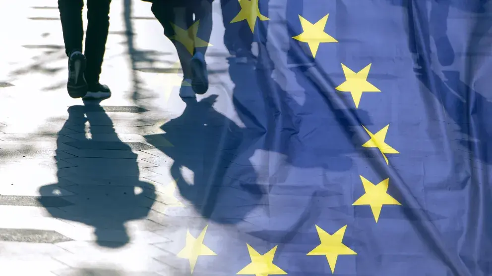 EU Flagge und ein Foto von zwei Personen bzw. deren Schatten am Boden