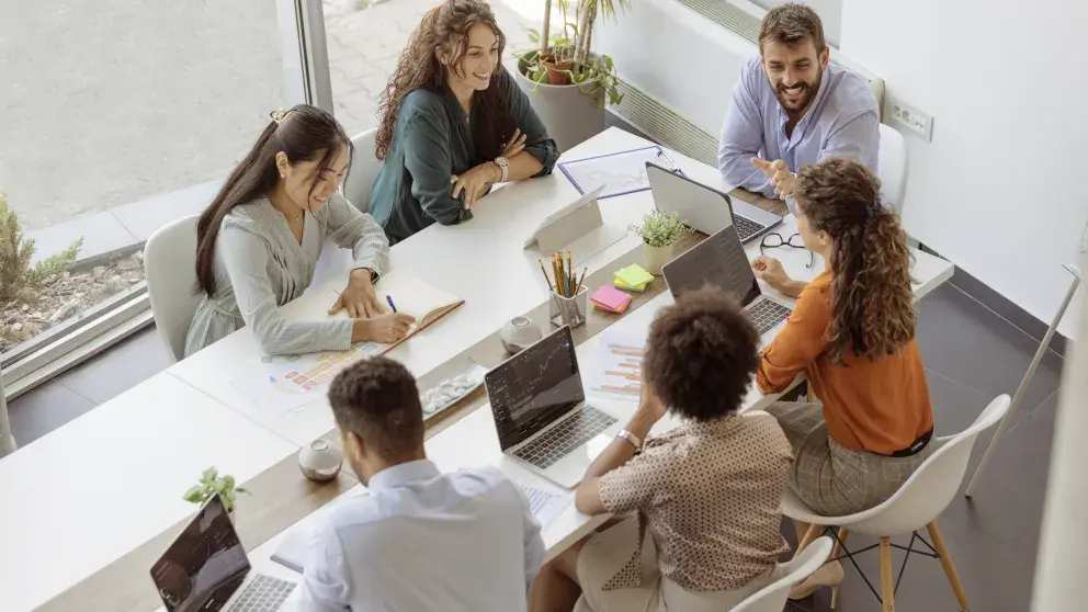 Verschiedene Geschäftsleute diskutieren gemeinsam bei einer Besprechung an einem Tisch in einem modernen Büro