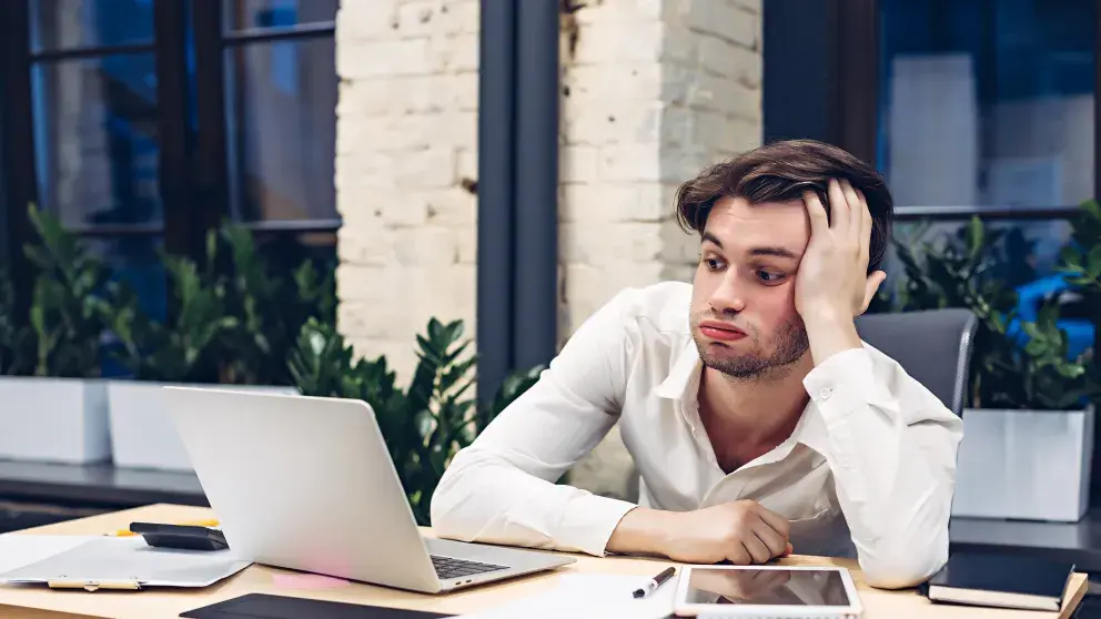 Frustrierter Geschäftsmann arbeitet am Laptop im Büro Stockfoto