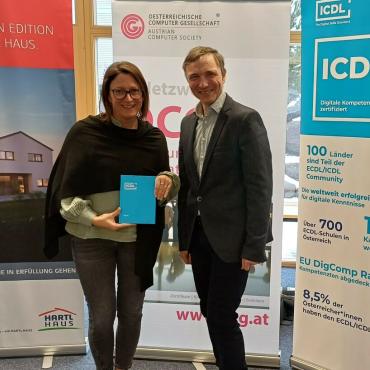 Sonja Früchtl von Hartl Haus und OCG Generalsekretär Ronald Bieber mit ICDL Roll-Up und ICDL Notizbuch im Hintergrund OCG und Hartl Haus Roll-up. C: Bernahrd Schabauer