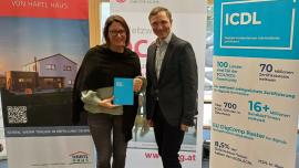 Sonja Früchtl von Hartl Haus und OCG Generalsekretär Ronald Bieber mit ICDL Roll-Up und ICDL Notizbuch im Hintergrund OCG und Hartl Haus Roll-up. C: Bernahrd Schabauer